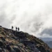 7 definitions of leadership represented by leaders climbing up a mountain trail.