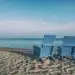 two chairs on a beach looking out over the ocean